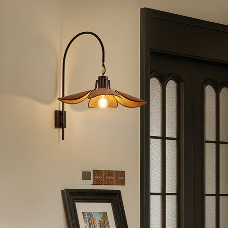 Sconce lit beside a tall dark doorway above framed prints and a curtain