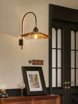 Sconce lit beside a dark door above a sideboard with a framed print
