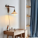 The swing arm lamp lit above a wood desk beside a blue curtain