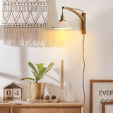 The curved arm version above a dresser with a plant and a woven wall hanging
