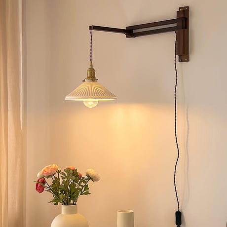 The lamp lit above a vase of flowers, its cord running down the wall