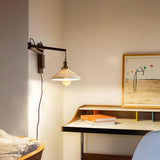 The lamp reaching over a writing desk with a framed print on the wall