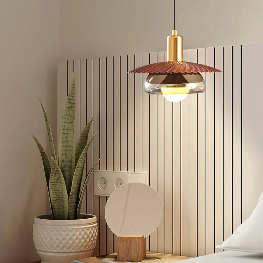 The walnut grain disc lit on its brass stem against a slatted wood wall