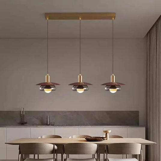 Three walnut grain discs lit in a row above a pale dining table