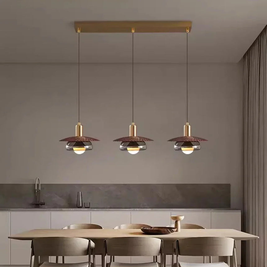 Three walnut grain discs lit in a row above a pale dining table