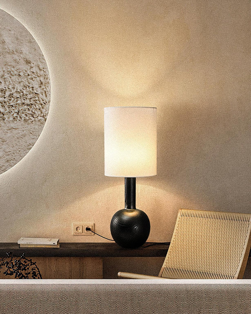 The black version lit on a low table beside a cane chair