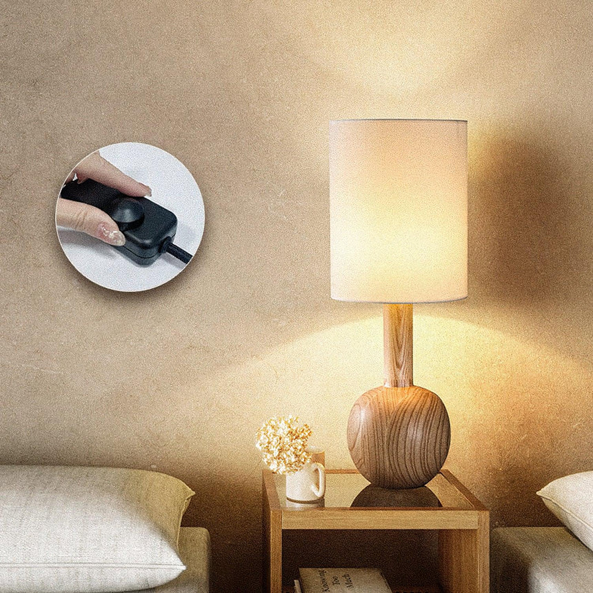 Walnut table lamp lit with an inset view of the control on the cord