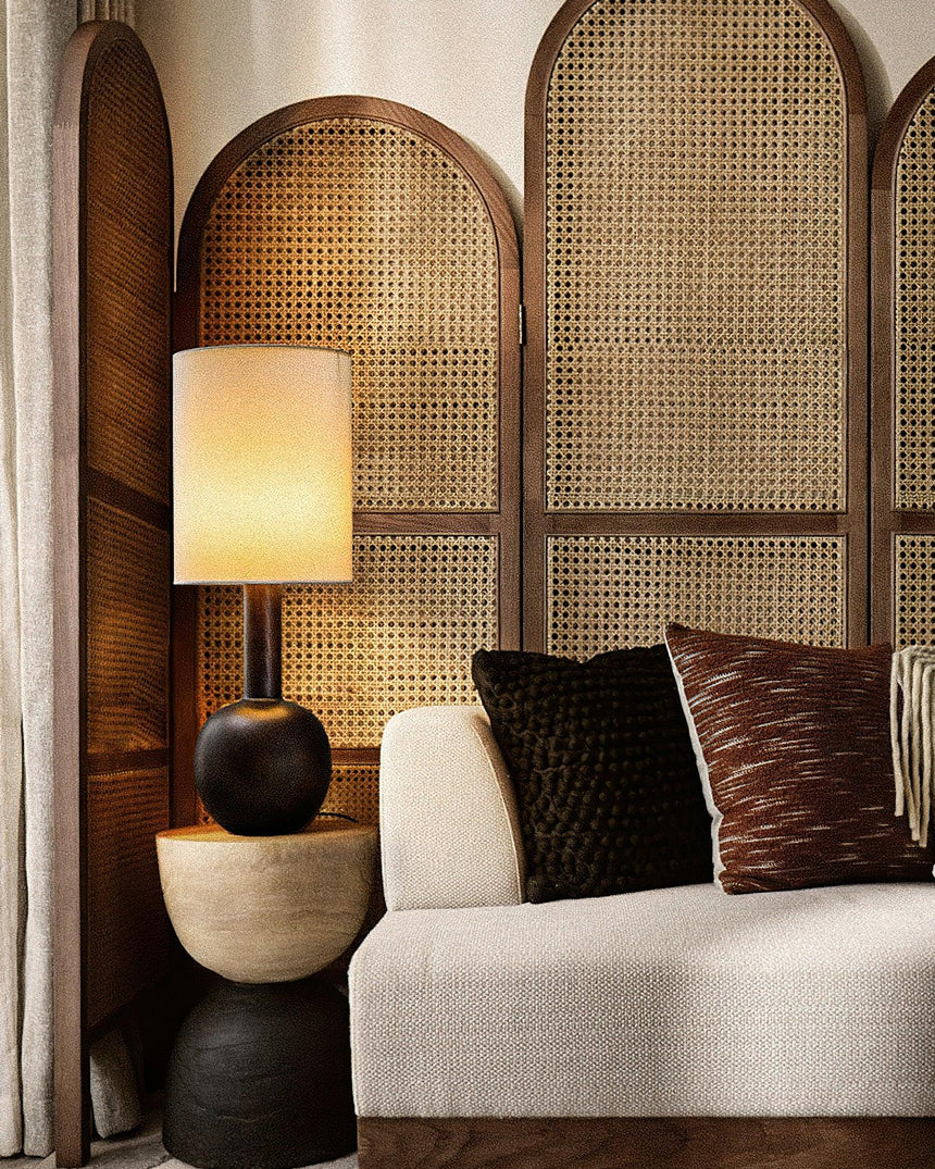 Walnut table lamp lit on a side table beside a pale sofa