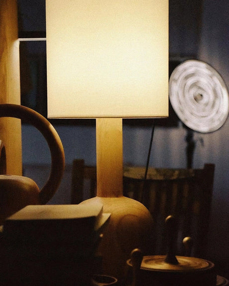 Walnut table lamp lit close in a warm room with brass objects