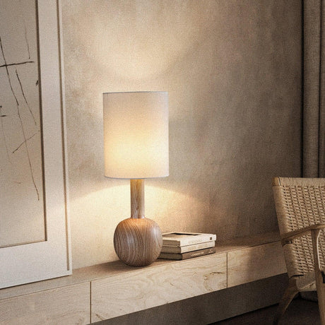 Walnut table lamp lit on a plaster ledge beside stacked books