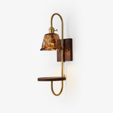 Walnut wall sconce with a shelf and an amber glass shade on a brass arm
