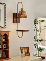 Sconce lit beside a tall mirror and a cabinet with framed photographs