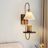 Sconce lit above a cane headboard with dried flowers on a table