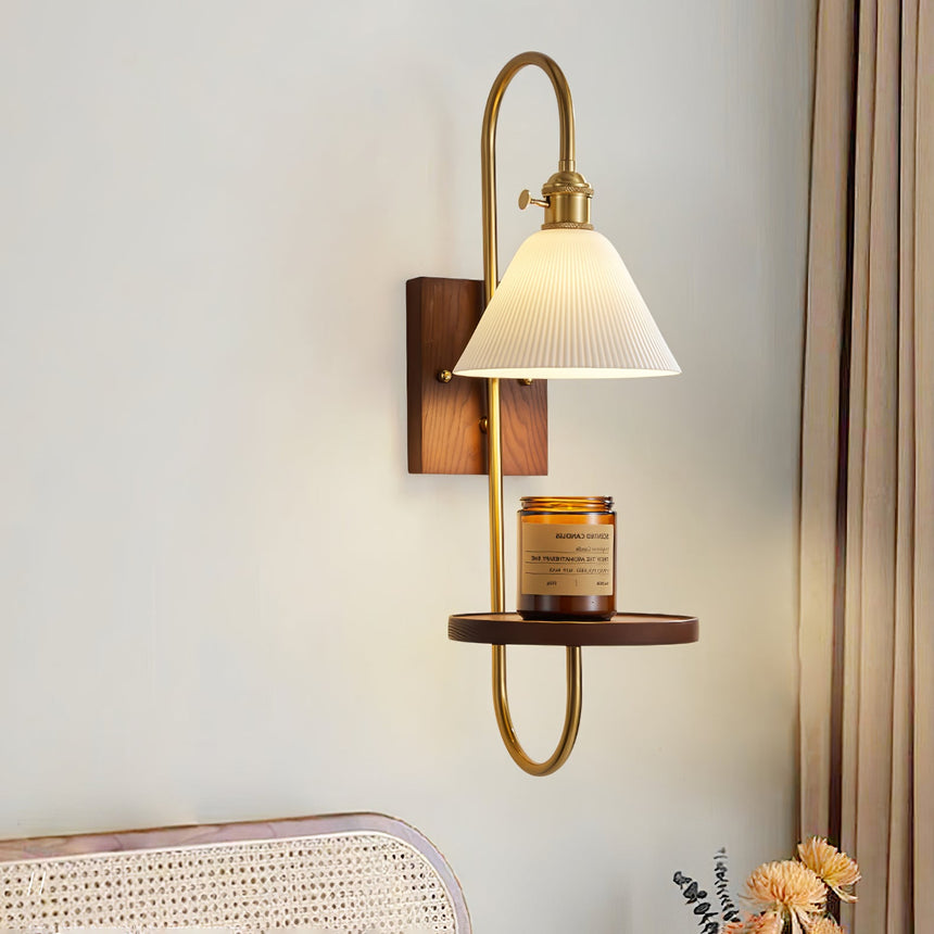 Sconce lit above a cane headboard with dried flowers on a table