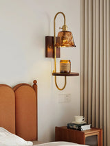 Sconce lit above a wood nightstand beside a bed with pale bedding