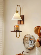 Sconce lit above a dresser beside a round mirror and small objects
