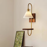Sconce lit beside a framed print, a candle jar on the wood shelf
