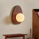 Sconce lit above a wood console with a woven basket and a cane chair