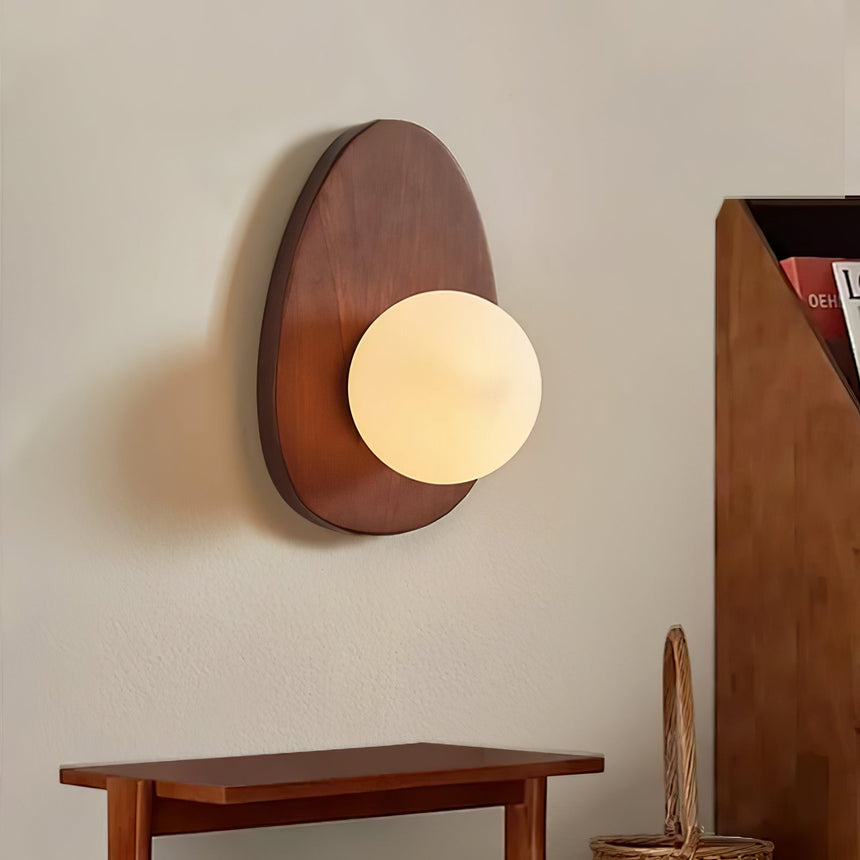 Sconce lit above a wood console with a woven basket and a cane chair