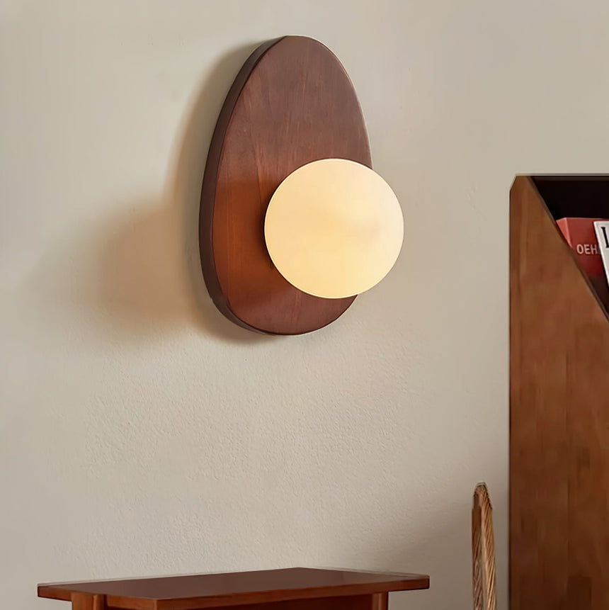 Sconce lit in an entry above a wood console beside a cane backed chair