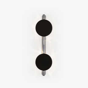 Wall light with two black discs on a polished rod, soft light rippling behind them