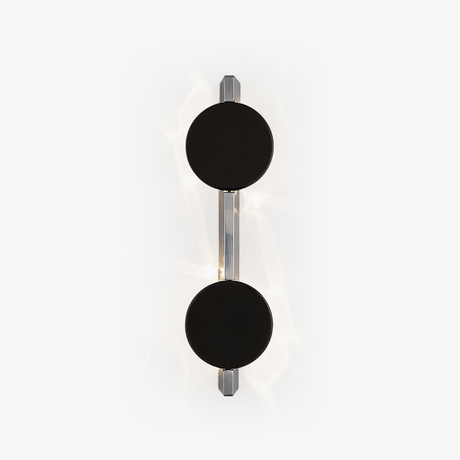Wall light with two black discs on a polished rod, soft light rippling behind them