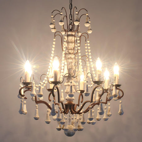 The chandelier lit warm, showing the column, the arms and the bead drops