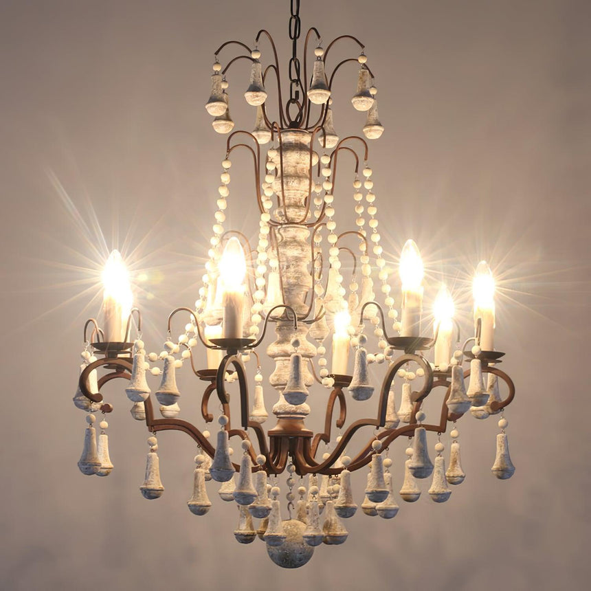 The chandelier lit warm, showing the column, the arms and the bead drops