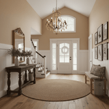 Hung in an entry hall above a round rug with a console, mirror and staircase