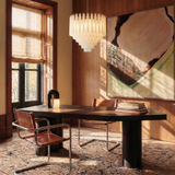 The fitting lit above a dark table with a leather chair, a window and a rug