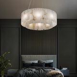 The lit drum in a bedroom above a bed with a paneled wall and a plant