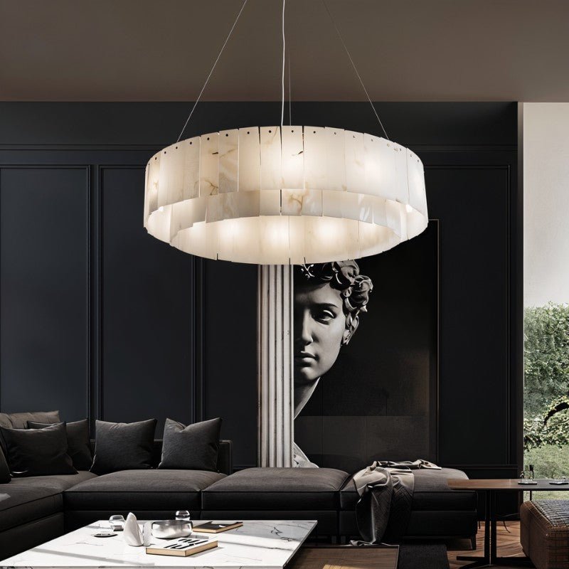 The lit drum in a dark room above a table with a sculpture on the wall