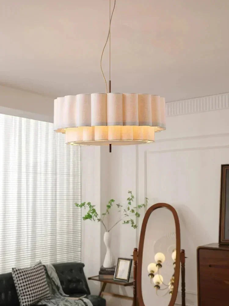 White drum pendant light lit in a bright room with sheer curtains and a floor mirror