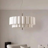 White drum pendant light lit above a sofa in a pale living room