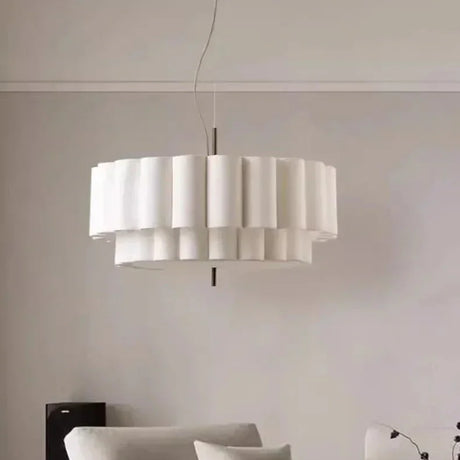 White drum pendant light lit above a sofa in a pale living room