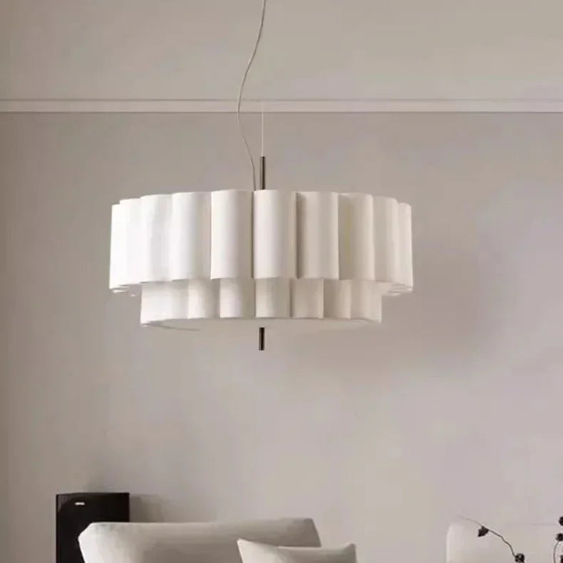 White drum pendant light lit above a sofa in a pale living room