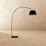 The arm rising from its rectangular stone base and curving out toward the shade