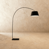 The same curved arm with a black fabric drum shade above a dark stone base