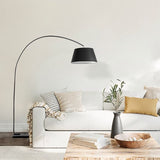 The black shade arching over a white sofa with cushions, a low table and books