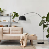 The lamp arching over a bench beside open shelving with plants and a stool
