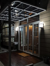 The light lit on dark cladding beside a glass door onto a covered deck at night
