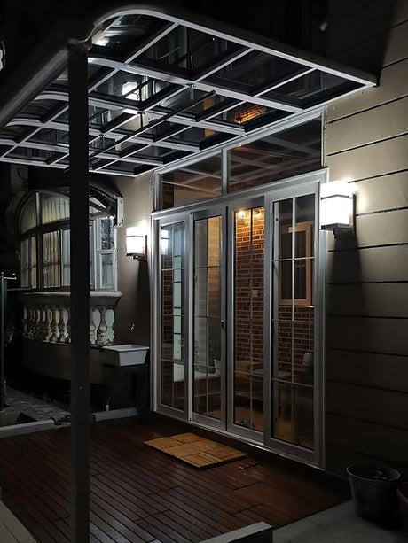The light lit on dark cladding beside a glass door onto a covered deck at night