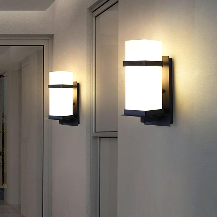 Two lights lit on walls between glass doors in a covered walkway