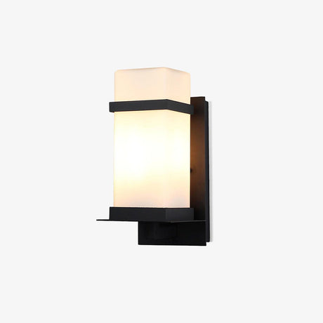 White outdoor wall light, a frosted white glass cube held in a black metal frame, lit