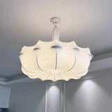 White pendant lights with a layered silk shade lit above a dining table