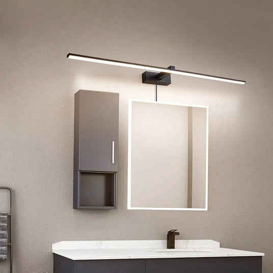Dark bar lit above a lit mirror beside a tall cabinet over a wide basin