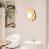 Plug in sconce lit on a plaster wall beside a plant and a stone basin