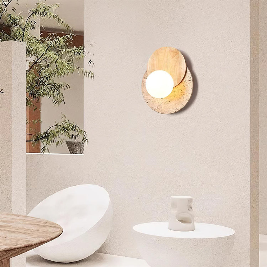 Plug in sconce lit on a plaster wall beside a plant and a stone basin