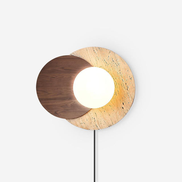 White plug in wall sconce, a glass orb between a walnut and a travertine disc