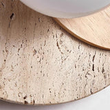 Close view of the porous travertine disc meeting the glass orb